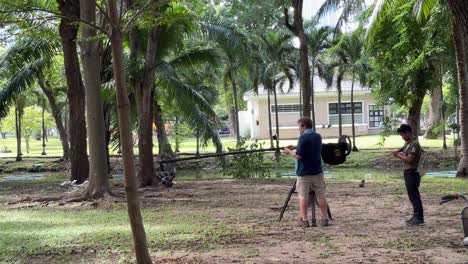 Professional-videographers-carefully-handle-the-camera-types-of-equipment-while-filming-in-Lumpini-Park,-Bangkok,-Thailand