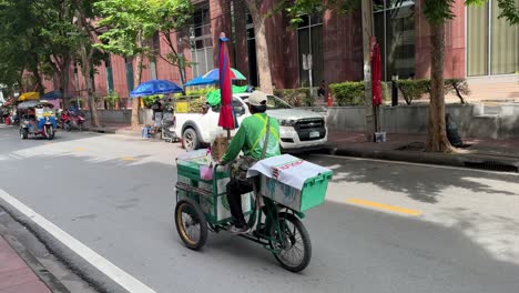 Local-vendor-cycling-his-tricycle-truck-on-the-street-in-Saladaeng,-Bangkok,-Thailand