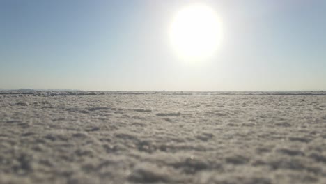 Stationary-ground-level-shot-of-the-Salt-Flats-with-a-glaring-sun-hovering-over-the-horizon