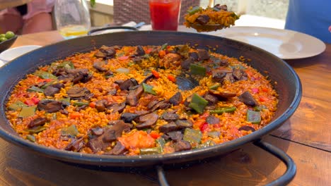 Scooping-with-a-big-spoon-traditional-Spanish-Paella-dish-with-vegetables-in-a-restaurant,-tasty-cooked-rice-with-vegetables,-Marbella-Spain,-4K-shot