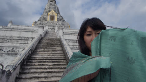 Eine-Frau-Verbirgt-Ihr-Gesicht-Mit-Einem-Schleier-Im-Buddhistischen-Tempel-Wat-Arun,-Dem-Tempel-Der-Morgenröte,-Der-Am-Ufer-Des-Flusses-Chao-Phraya-Liegt