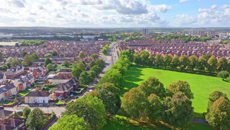 Vibrant-green-field-lined-with-trees-on-edge-of-suburban-red-roofed-homes-in-Doncaster-England