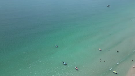 Aerial-shot-of-beach-with-few-people-and-boats-near-the-shore-line