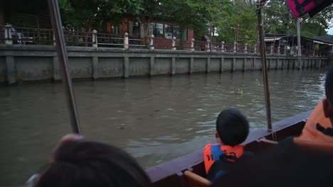 Tourists-on-this-boat-looking-to-the-left-as-another-touring-boat-passes-by-with-tourist-in-it-in-Amphawa-Floating-Market,-Thailand