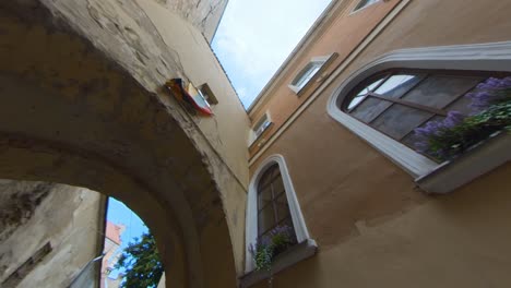 Lithuanian-Flag-Above-the-Arch-in-the-Narrow-Old-Town-Street-in-Vilnius,-Lithuania