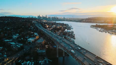 Aerial-rising-shot-overhead-Lake-Union-bridge-at-sunset-overlooking-Seattle