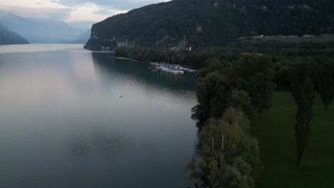 Aerial-footage-of-Walensee's-shoreline-with-silver-blue-waters-and-a-couple-of-sailboats-docked-in-the-small-marina