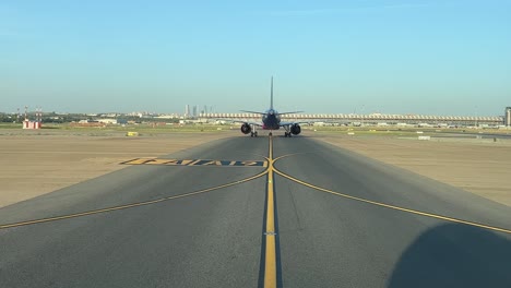External-view-shot-from-a-jet-cockpit-of-an-airplane-taxiing-ahead-in-sunny-summer-morning,-with-the-silhouette-of-the-jet-on-the-taxiway