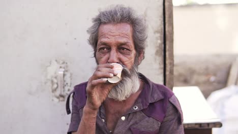 Un-Anciano-De-Las-Calles-De-Rajasthan,-India,-Bebiendo-Té-Mientras-Sonríe.