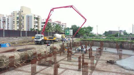 Aerial-ground-view,-construction-work-of-high-rise-building-is-going-on-in-which-basement-is-being-built-and-concrete-and-cement-filling