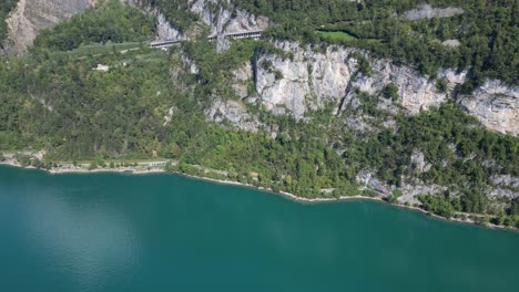 A-bird's-eye-view-of-the-lush-green-mountain-hills-surrounding-the-clear-turquoise-waters-of-Walensee-in-Switzerland