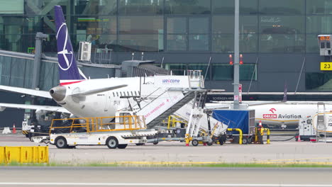 Avión-Con-El-Logotipo-De-Cola-Púrpura-Atracado-En-Una-Terminal-Del-Aeropuerto-De-Gdansk,-Rodeado-De-Equipo-Y-Tripulación-De-Apoyo-En-Tierra