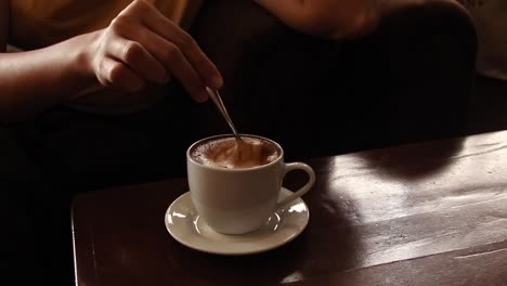 Frau-Rührt-Gemächlich-Eine-Tasse-Cappuccino,-Während-Sie-In-Einem-Gemütlichen-Café-Entspannt,-Herbststimmung-Und-Ästhetik