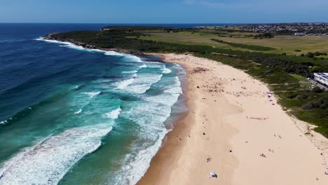 Drone-aerial-landscape-view-surfing-and-waves-sandy-beach-travel-tourism-coastline-headland-holiday-destination-Maroubra-Beach-Randwick-NSW-Sydney-Australia-4K