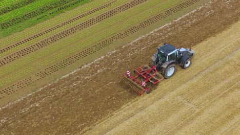 Tractor-in-slow-motion-on-crop-field,-high-angle-view-from-the-corner-zooming-in
