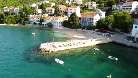Touristen-Auf-Betonpier-Mit-Schwimmenden-Booten-Im-Dorf-Brist,-Dalmatien,-Kroatien