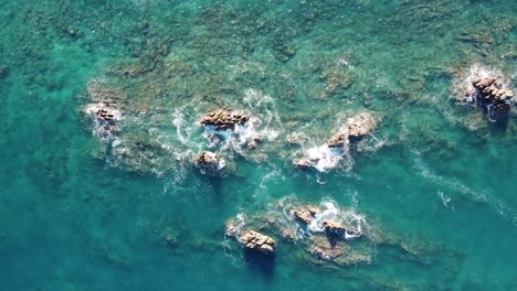 Aerial-view-of-rocky-outcrops-amidst-clear-blue-waters