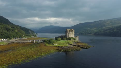 Eilean-Donan-Castle-in-the-highlands-of-Scotland,-UK-_-drone-shot-sunset-with-beautiful-lake