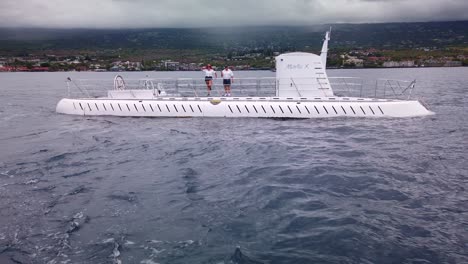 Gimbal-wide-shot-from-a-moving-boat-pulling-away-from-the-Atlantis-Submarine-while-the-crew-waves-goodbye-off-the-coast-of-Kailua-Kona,-Hawai'i