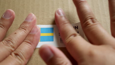 Hands-applying-MADE-IN-ISRAEL-flag-label-on-a-shipping-box-with-product-premium-quality-barcode