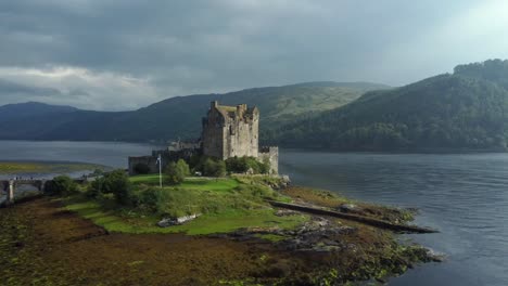 Eilean-Donan-Castle-in-the-highlands-of-Scotland,-UK-_-drone-shot-sunset-with-beautiful-lake,-orbiting-slowly