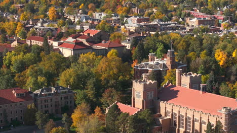 Aerial-up-close-view-of-CU-Boulder-campus-surrounded-by-green-and-yellow-fall-trees-with-the-rocky-flatiron-mountains-in-the-background-in-the-front-range-of-Colorado