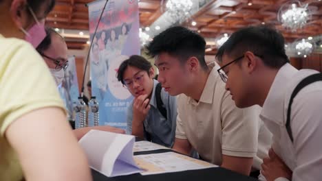 Group-of-Young-Men-Listening-to-Explanation-During-Job-Fair