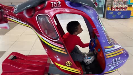 3-jähriger-Schwarzer-Junge-Genießt-Eine-Münzbetriebene-Fahrt-In-Einem-Spielzeughubschrauber-In-Einem-Einkaufszentrum