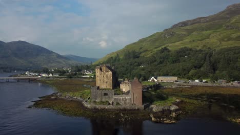 Eilean-Donan-Castle-in-the-highlands-of-Scotland,-UK-_-drone-shot-sunset-with-beautiful-lake-zooming-out