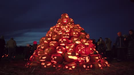 People-admiring-a-large-pile-of-Jack-o'-lanterns