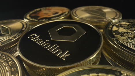 Rotating-chainlink-coin-on-a-pile-of-crypto-coins-turning-on-black-background,-crypto-market,-4K-shot