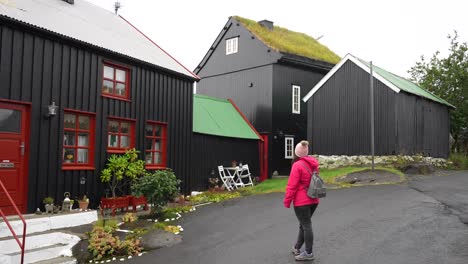 Woman-looking-at-black-wooden-houses-with-tar-and-turf-roofs-in-Torshavn