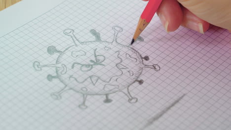 Close-up-of-a-female-hand-drawing-a-cartoon-virus-with-a-pencil