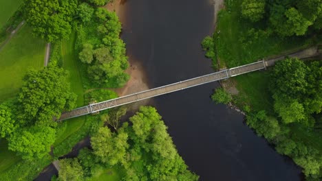 Aerial-drone-footage-of-a-bridge-over-water-in-a-green-park-in-summer