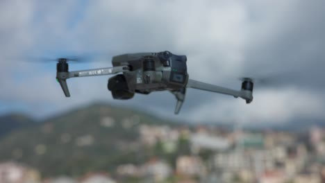 Atemberaubender-Blick-Auf-Die-Drohne-DJI-Mavic-3-Pro,-Die-In-Der-Luft-Fliegt-Und-Rotiert,-Mit-Der-Stadt-Im-Hintergrund