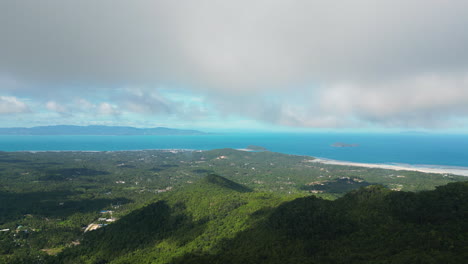 Aerial-wide-shot-over-green-Koh-Phangan-Island-and-blue-ocean-during-cloudy-day---panorama-view