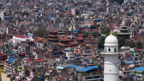 White-tower-Dharahara,-Kathmandu-Durbar-Square,-urbanization,-unmanaged-architectural-buildings,-modern-city,-trees,-drone-shot-4K
