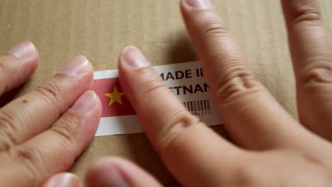 Hände-Bringen-Das-Etikett-„Made-In-Vietnam“-Mit-Der-Flagge-„Made-In-Vietnam“-Auf-Einem-Versandkarton-Mit-Einem-Barcode-In-Premiumqualität-An