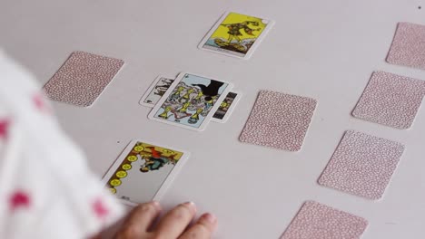 Tarot-reader-flipping-cards-of-Celtic-cross-spread,-over-the-shoulder-shot