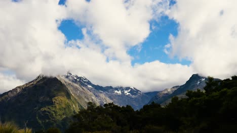 Timelapse-De-Nubes-Pasando-Sobre-Montañas-Boscosas-Con-Picos-Nevados