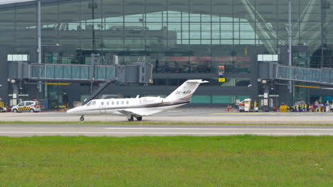 Private-jet-on-a-runway-with-an-airliner-and-airport-terminal-in-the-background