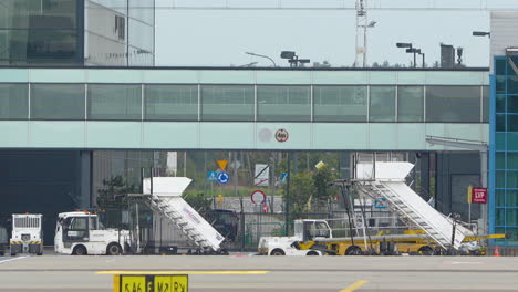 Modernes-Flughafenterminal-Mit-Bodenausrüstung-Und-Schildern-Im-Vordergrund