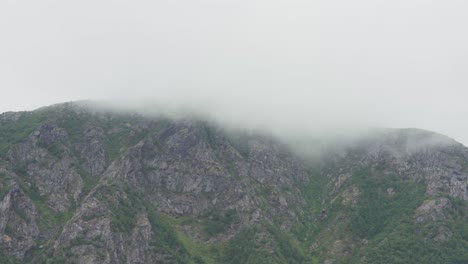 Clouds-Enveloping-Massif-Rock-Mountains-Over-Medby-Village,-Senja-Island,-Norway