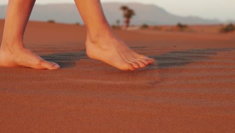 Detail-of-young-caucasian-female-legs-walking-on-sand-in-the-desert-during-sunset
