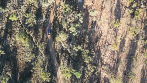 Aerial-of-a-car-driving-on-a-winding-outback-road-in-Queensland,-Australia