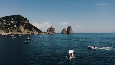 Drone-shot-of-boats-traveling-along-Italy's-beautiful-shoreline