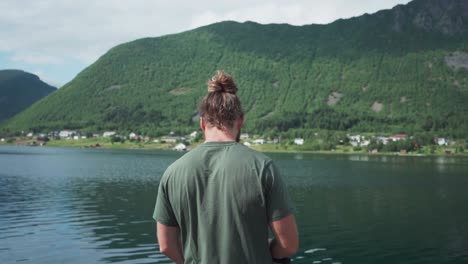 Norwegian-Guy-Fishing-On-The-Lakeshore-Near-Medby-Village,-Senja,-Norway