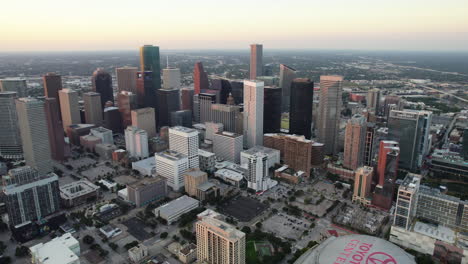 Aerial-view-backwards-over-the-streets-of-Houston,-sunset-in-TX,-USA