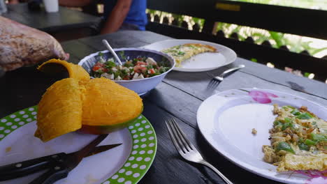 Egg-omelette,-fresh-mango,-and-Greek-salad-on-rustic-outdoor-table