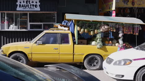 Yellow-pickup-truck-loaded-with-fruit-and-vegetables-at-street-market